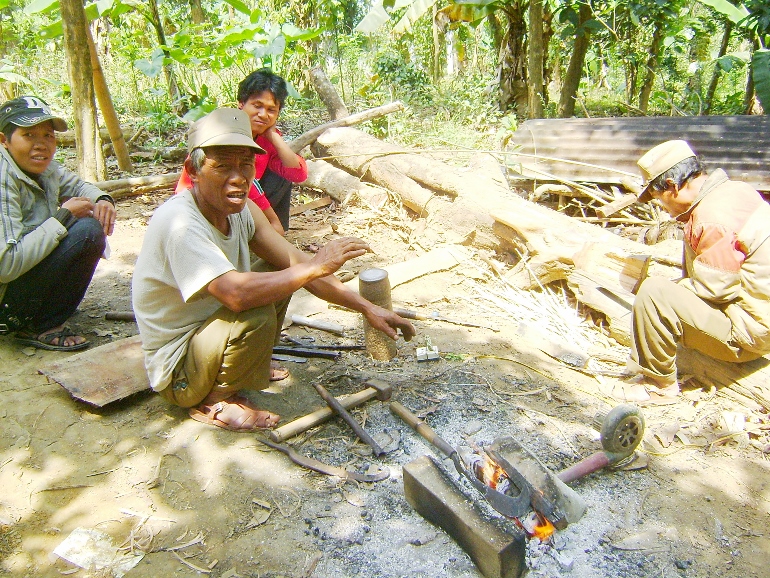 Ho Kan Son (left) and his two sons forge cutting tools out of metal from unexploded bombs for a living. (Peter Nguyen)