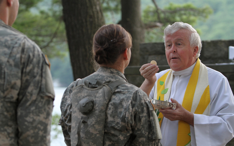Augustinian Fr. Edson Wood, brigade chaplain at the U.S. Military Academy, distributes Communion during Mass at Camp Buckner in West Point, N.Y., in 2011. (CNS/Gregory A. Shemitz)