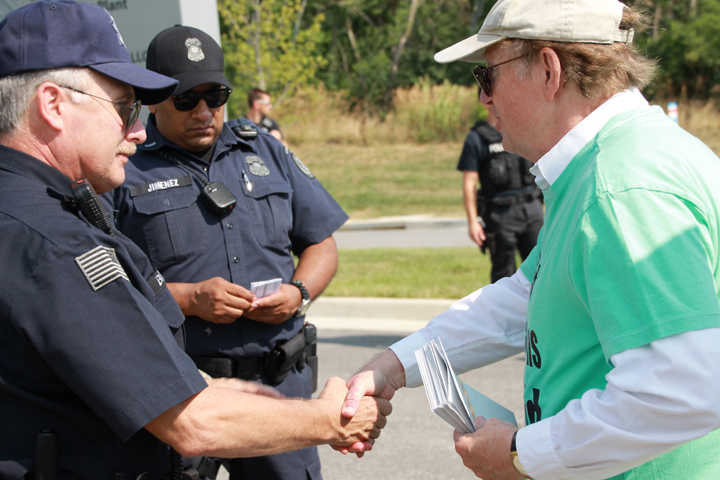 Protest organizer Henry Stoever shakes hands with police after the arrest of line crossers Saturday at the National Security Campus in Kansas City, Mo. (NCR photo/Kate Simmons)