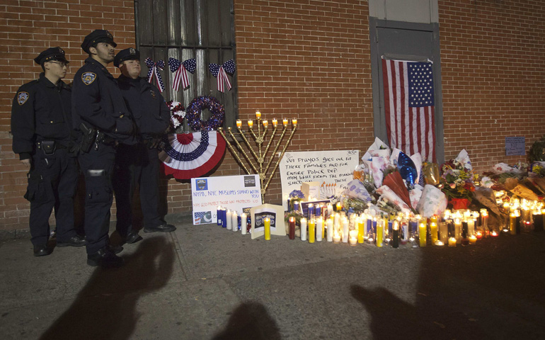 Police officers stand by a makeshift memorial solemn during a late night vigil Monday at the site where two police officers were shot in the head in the Brooklyn borough of New York. (CNS/Reuters/Carlo Allegri)