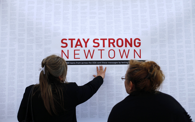 Women look at a printout of text messages Dec. 18, 2012, at a memorial site in Newtown, Conn. (CNS/Reuters/Joshua Lott)