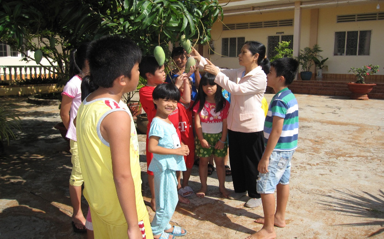 Sr. Mary Nguyen Thi Phuong Lan, a Dominican Sister of Our Lady of the Rosary in the Phu Cuong Diocese in Hanoi, Vietnam, shows children a mango tree grown without using the chemicals and growth substances. (Provided photo)