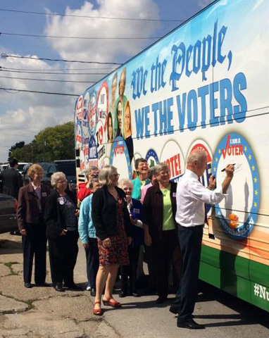 Vice President Joe Biden signs his name to the NETWORK Nuns on the Bus official vehicle for the 2014 "We the People, We the Voters" tour after speaking at the kick-off rally Wednesday in front of the Iowa State Capitol. (Photo courtesy of NETWORK)