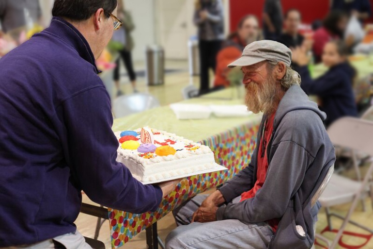 A volunteer James Silva presents an Our Father's Table guest with a birthday gift. (Courtesy of Our Father's Table)