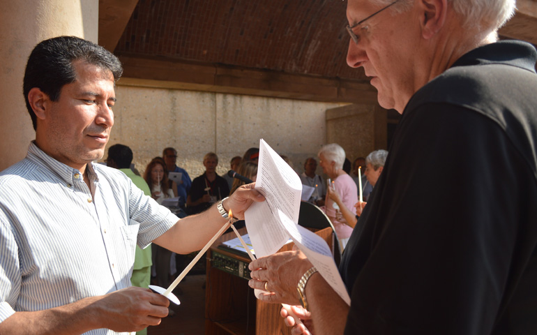 Jose Henriquez, left, and Tom Wannemuehler light each other's candles June 15 during a prayer service at The Martin Luther King Jr. Center for Nonviolent Social Change. (Veronica O'Neill)