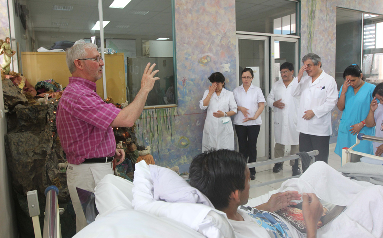 Maryknoll Fr. Joe Fedora prays with staff and patients in the Santa Rosa infectious diseases ward in Lima's Dos de Mayo Hospital. (CNS/Barbara Fraser) 