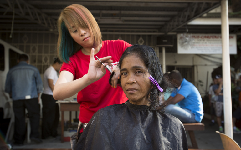 A volunteer cuts the hair of a homeless woman at a church in Manila, Philippines, Jan. 9. (CNS/Tyler Orsburn)