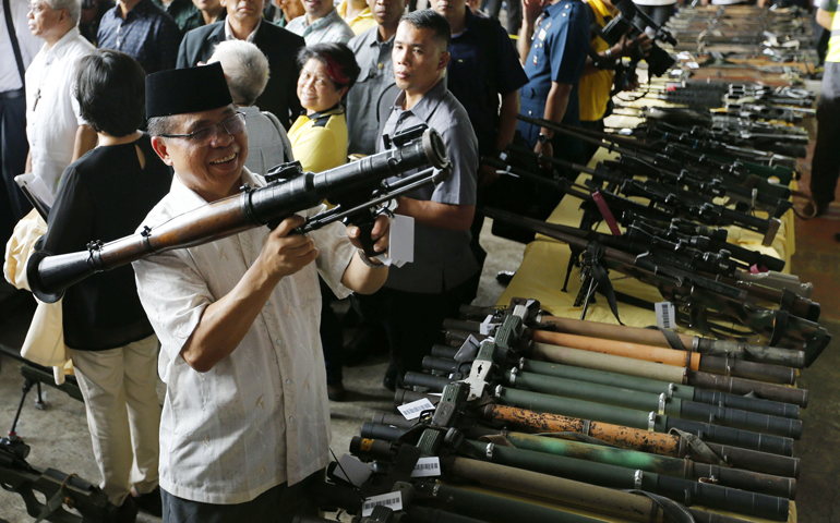 Moro Islamic Liberation Front Chairman Al-Haj Murad Ebrahim holds a surrendered rocket-propelled grenade launcher Tuesday during the first phase of the decommissioning of rebel weapons in Maguindanao, Philippines. (CNS/EPA/Ritchie B. Tongo)