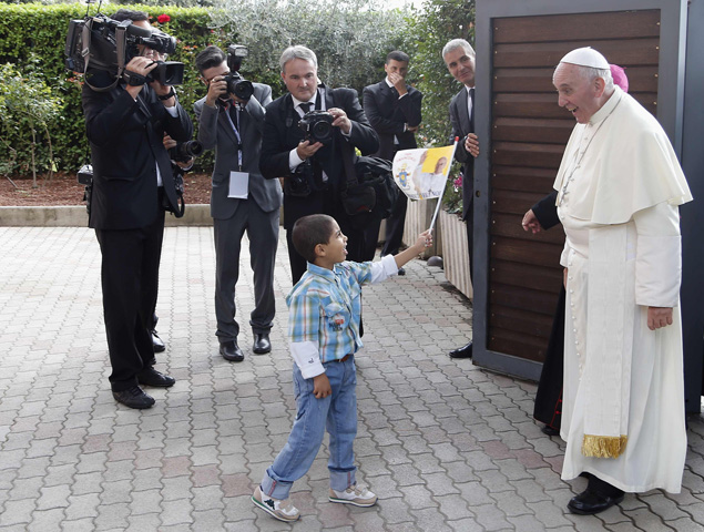 A child waves a flag as Pope Francis arrives Friday at the Caritas residence in the Italian pilgrimage town of Assisi. (CNS/Reuters/Stefano Rellandini)