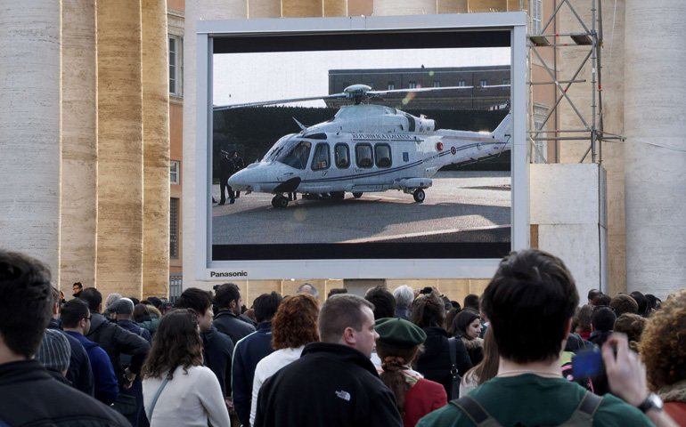 People in the Vatican's St. Peter's Square watch a giant screen showing the helicopter waiting to carry Pope Benedict XVI to the papal summer residence at Castel Gandolfo, Italy, on Thursday, the final day of his papacy. (CNS/Reuters/Stefano Rellandini)