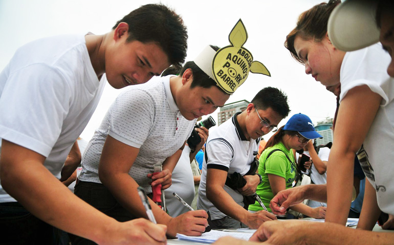 Filipinos sign a petition to scrap the pork barrel funds during a protest Monday at Luneta Park, Manila, Philippines. (Roy Lagarde) 