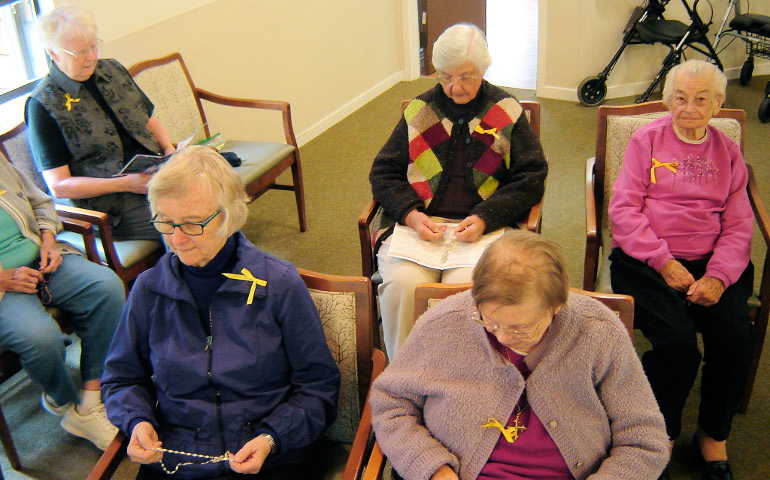 A group of Dominican sisters pray the rosary in the chapel at Lourdes Convent in San Rafael, California. Their yellow ribbons mean support for taking in two single mothers and their children. (Courtesy of the Dominican Sisters of San Rafael)