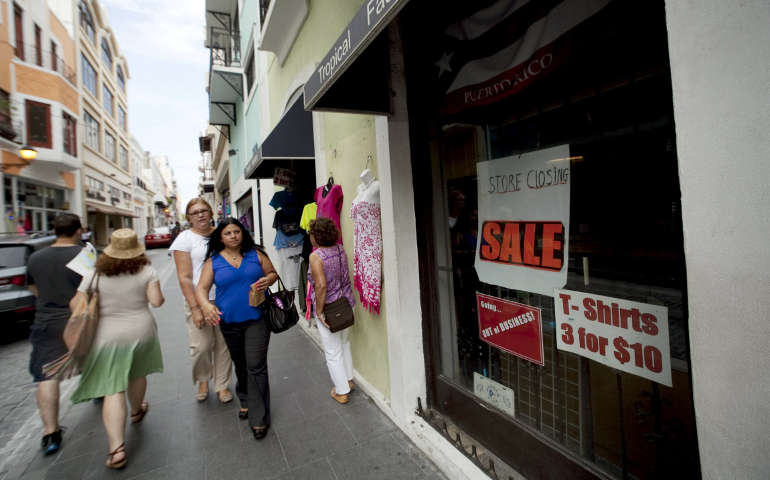 People walk past a closed store in San Juan, Puerto Rico, July 31. As Puerto Rico's government gets closer to a critical financial deadline regarding its $72 billion "unpayable" debt, religious leaders appeal for help. (CNS/Alvin Baez, Reuters)
