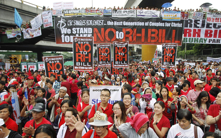 Protesters display anti-Reproductive Health Bill placards during a rally in August at the EDSA Shrine in Manila. Thousands of demonstrators took part in a protest lead by Catholic bishops opposing the bill, a proposed measure allowing the government to distribute contraceptives. (CNS/Reuters/Erik De Castro)