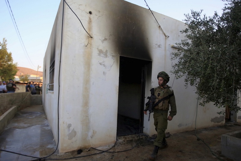 An Israeli soldier walks past a house that had been torched in a suspected attack by Jewish extremists killing an 18-month-old Palestinian child, injuring a four-year-old brother and both their parents at Kafr Duma village near the West Bank city of Nablus July 31, 2015. (RNS photo courtesy of REUTERS/Abed Omar Qusini)