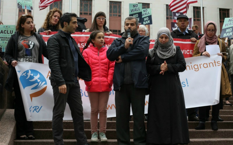 Mustafa Al-Mustafa, center right, a refugee from Syria, speaks with the help of a translator, Moh Kilani, left, while joined by his wife, Jamila Al-Mustafa, right, and daughter, Yamama, 11, center left, during a protest against President Trump's travel ban outside of the U.S. Court of Appeals on May 15, 2017, in Seattle, Washington. (Reuters/David Ryder)