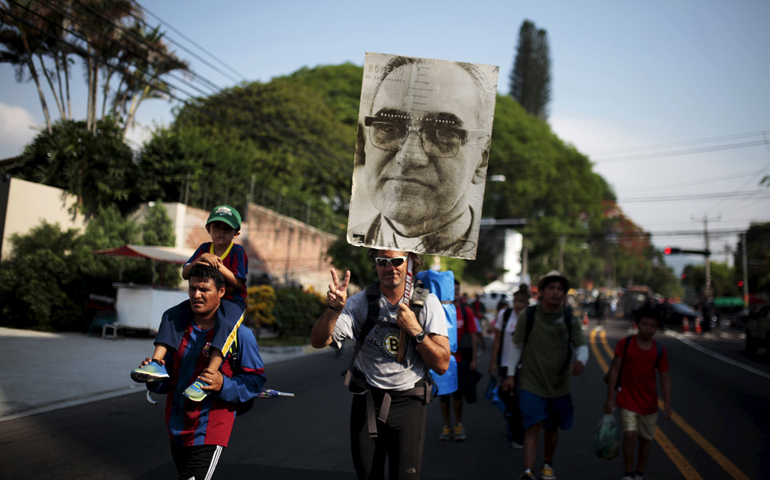 A pilgrim carries a poster of Archbishop Oscar Romero at El Salvador del Mundo Square on May 22, the day before his beatification ceremony in San Salvador. (CNS/Reuters/Jose Cabezas)
