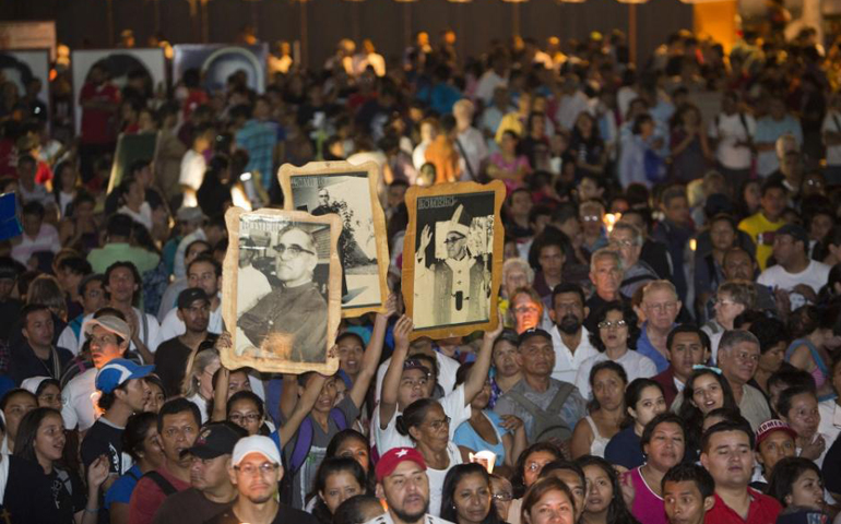 People hold images of Archbishop Oscar Romero during an outdoor Mass March 21, 2014, in San Salvador to mark the 35th anniversary of his death. (CNS/Octavio Duran)
