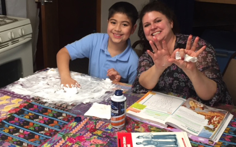 A tutor works with an English as a second language student at Centro San Pablo, a drop-in center for migrants in Salem, Ohio, run by St. Paul Church. They are writing words in shaving cream. (Sr. Rene Weeks)