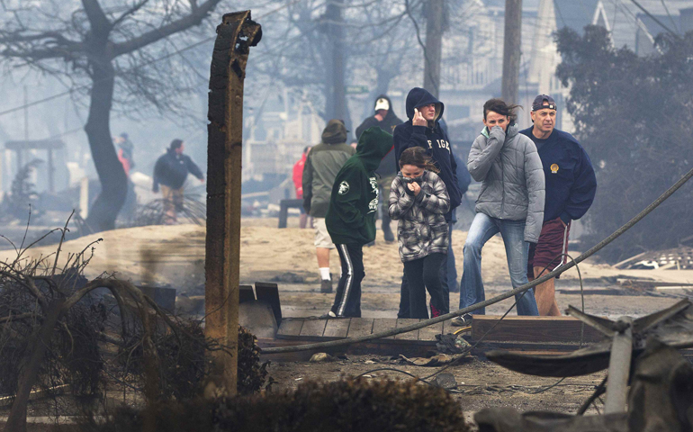 People stand among homes destroyed by fire and the effects of Hurricane Sandy Tuesday at the Breezy Point section of Queens borough in New York. (CNS/Reuters/Shannon Stapleton)