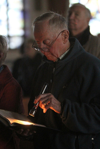 Harold Scott uses a flashlight during an early morning All Saints' Day Mass on Thursday at Sts. Philip & James Church in St. James, N.Y. St. James was one of many communities on Long Island that remained without electricity three days after Hurricane Sandy swept through the region. (CNS/Gregory A. Shemitz) 