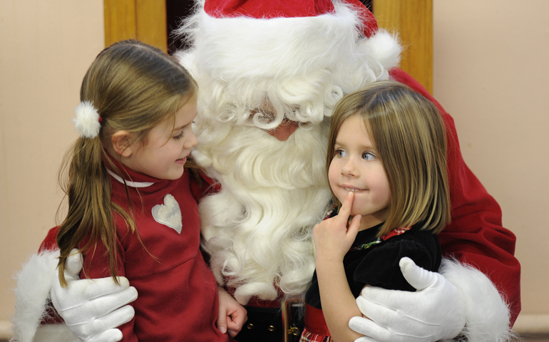 Nora Burroughs, left, and her sister, Cate, think about what they want for Christmas during the annual "Breakfast with Santa" in December 2012 at St. Joseph School in Auburn, N.Y. (CNS/Catholic Courier/Mike Crupi)
