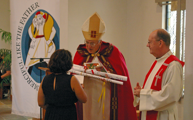 A representative from of one of the working groups at the diocesan synod hands her group's scroll of resolutions to Bishop Robert McElroy at the synod's conclusion. At right, Paulist Fr. John Hurley. (Denis Grasska photo/Southern Cross)