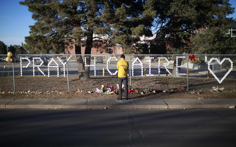 An Arapahoe High School student prays at the school Sunday in Centennial, Colo. Claire Davis, a 17-year-old senior, was shot in the head Friday by a heavily armed classmate who stormed the school. (CNS/Reuters/Rick Wilking)
