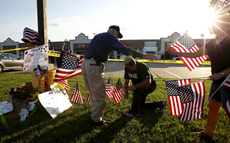 Mourners place flags at a makeshift memorial July 16 for shooting victims in front of the Armed Forces Career Center in Chattanooga, Tenn. (CNS/Reuters/Tami Chappell)