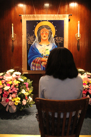 A visitor prays before a shrine to Our Lady of Light, featuring a painting by Oblate Br. Mickey O'Neill McGrath, at Blessed Virgin Mary Church in Darby, Pa. (CNS/CatholicPhilly.com/Sarah Webb)