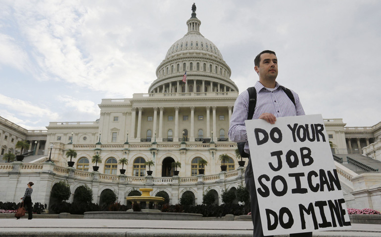 A furloughed federal employee holds a sign on the steps to the U.S. Capitol on Tuesday in Washington after the U.S. government shut down. (CNS/Reuters/Larry Downing)
