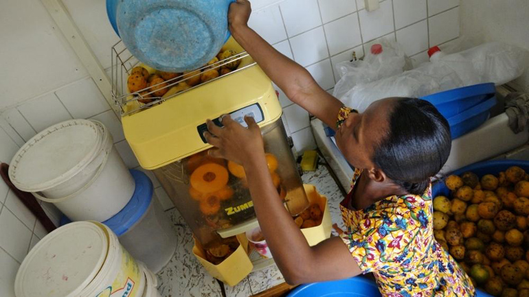 Sr. Mary Boatemaa loads the orange juicer with oranges. (GSR/Dana Wachter)