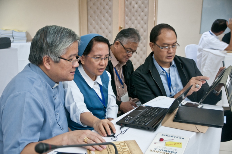 Daughters of St. Paul Sr. Mary Padilla helps CBCP President Archbishop Socrates Villegas (left) while Bishop Florentino Lavarias and Bishop Pablo David work on tasks during the CBCP pre-plenary media workshop being led by Seàn-Patrick Lovett in Manila Jan. 21-24. (Roy Lagarde)