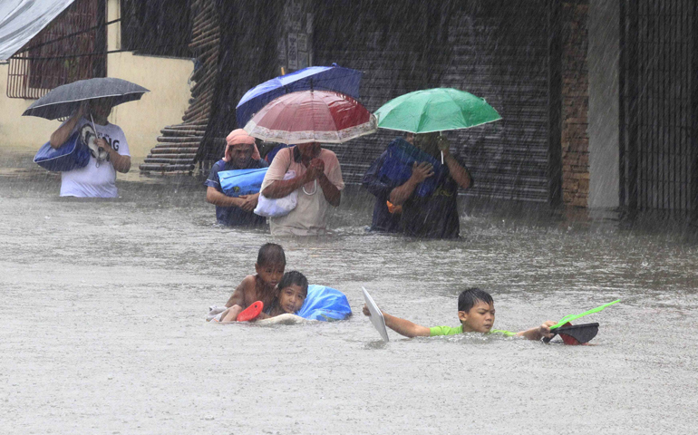People carry their belongings as they wade through a flooded street Friday after tropical storm Fung-Wong battered metro Manila, Philippines. (CNS/Reuters/Romeo Ranoco)