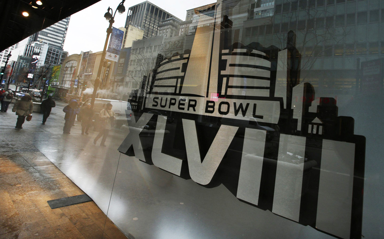 Pedestrians are reflected on windows displaying the Super Bowl icon Monday as preparations continued for Super Bowl XLVIII in New York. (CNS/Reuters/Eduardo Munoz)