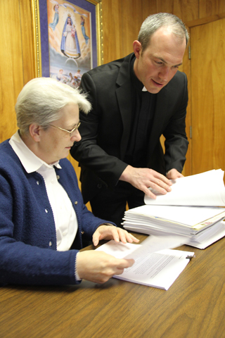 Fr. Christopher Singer, chancellor, and Spiritual Family Sr. Kathleen Dietz, vice chancellor, review the 5-inch-thick stack of responses to the Erie, Pa., diocese's survey for the synod on the family. (Mary Solberg)