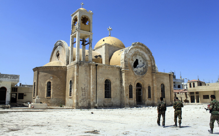 Soldiers loyal to the Syrian regime walk near a damaged church in Qusair, Syria, June 6. (CNS/Reuters/Rami Bleibel)