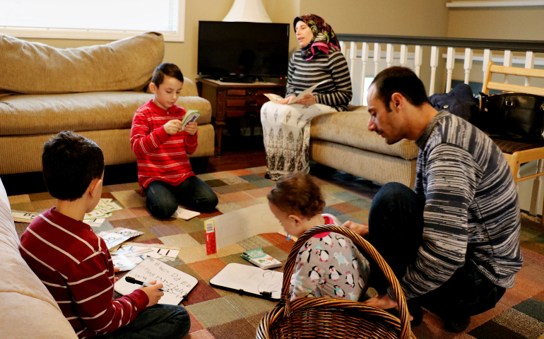 Syrian refugees Ahmed Al Kango and his wife, Sahar, help their children learn English in their home in Elkhorn, Nebraska. (CNS/Catholic Voice/Joe Ruff)