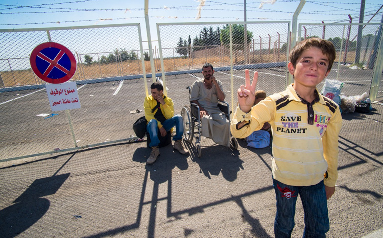 A Syrian refugee boy flashes a peace sign along the border in Kilis, Turkey, in mid-September. (CNS/The Catholic Register/Michael Swan)