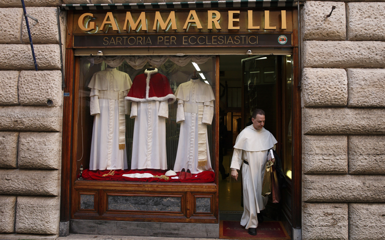 Dominican Fr. Thomas Petri, assistant professor of theology at Providence College in Rhode Island, leaves the Gammarelli clerical tailor shop Monday in Rome. Three sizes of cassocks for the future pope are displayed in the window. (CNS/Paul Haring)