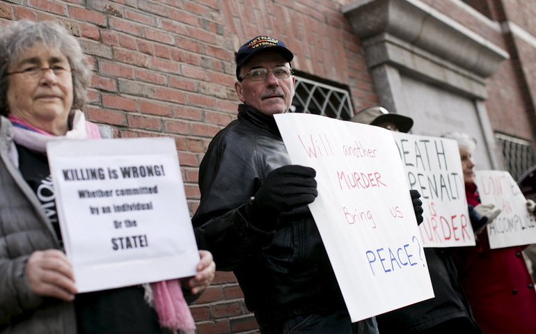 Protesters against the death penalty hold signs before closing arguments took place April 6 in the trial of accused Boston Marathon bomber Dzhokhar Tsarnaev at the federal courthouse in Boston. (CNS/Reuters/Dominick Reuter)
