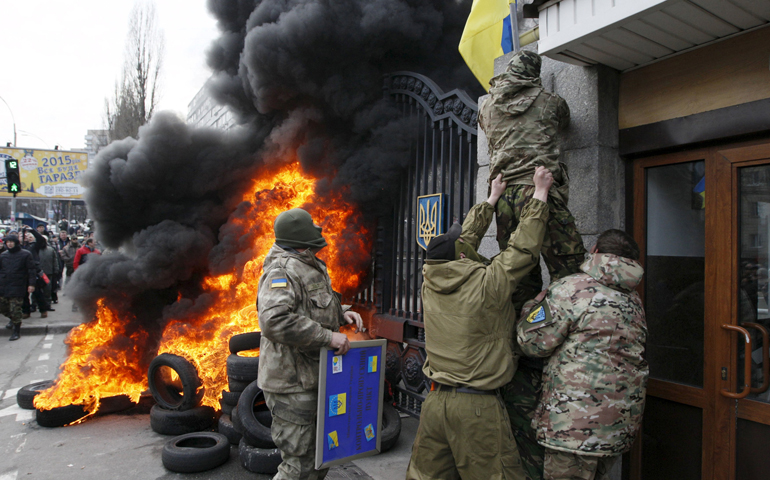 Servicemen from the Aydar battalion throw a Ukrainian flag from the building of Ukraine's Defense Ministry in Kiev during a Feb. 2 protest against the disbanding of the battalion. (CNS/Reuters/Valentyn Ogirenko)