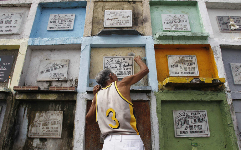 A man applies paint on his relative's tomb at a public cemetery Oct. 31, 2012, in Manila in preparation for All Saints' Day Nov. 1 and All Souls' Day Nov. 2. (CNS/Reuters/Romeo Ranoco)