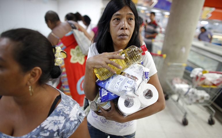 A woman carries products at a state-run supermarket Tuesday in Caracas, Venezuela. Sporadic shortages of basic goods in the country can turn a roll of toilet paper into a rare commodity. (CNS/Reuters/Jorge Silva)
