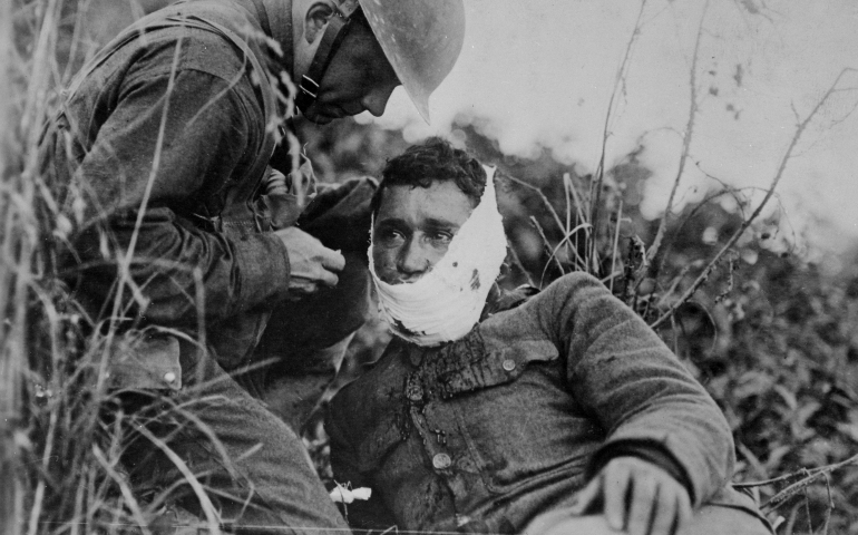 An American soldier wraps another soldier’s head wound at Varennes-en-Argonne, France, in September 1918. (National Archives)