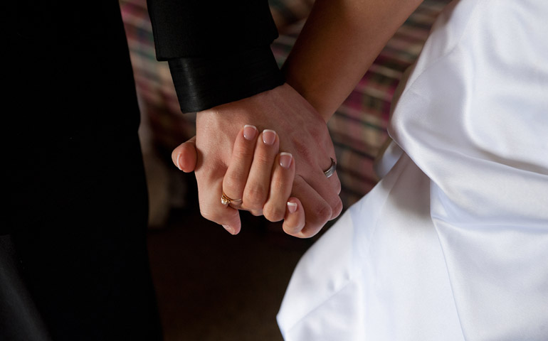 A groom and bride hold hands on their wedding day. (CNS file photo/Jon L. Hendricks)