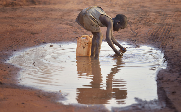 A girl fills a container with muddy water April 3 in the Ajuong Thok Refugee Camp in South Sudan. (CNS/Paul Jeffrey)