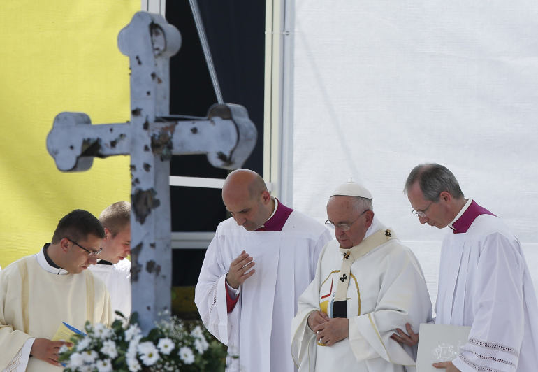 Celebrating Mass in Sarajevo’s Kosevo Stadium, Pope Francis walks near a cross punctured by ammunition during the 1992-1995 Bosnian War. (CNS/Paul Haring)