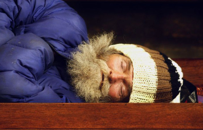 A man sleeps upon a pew in St. Boniface Church in San Francisco (Jeanette Antal)