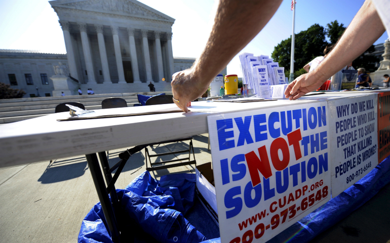 A member of the Abolition Action Committee hangs a sign in front of the Supreme Court in Washington during a 2008 vigil to abolish the death penalty. (CNS photo/Shawn Thew, EPA)